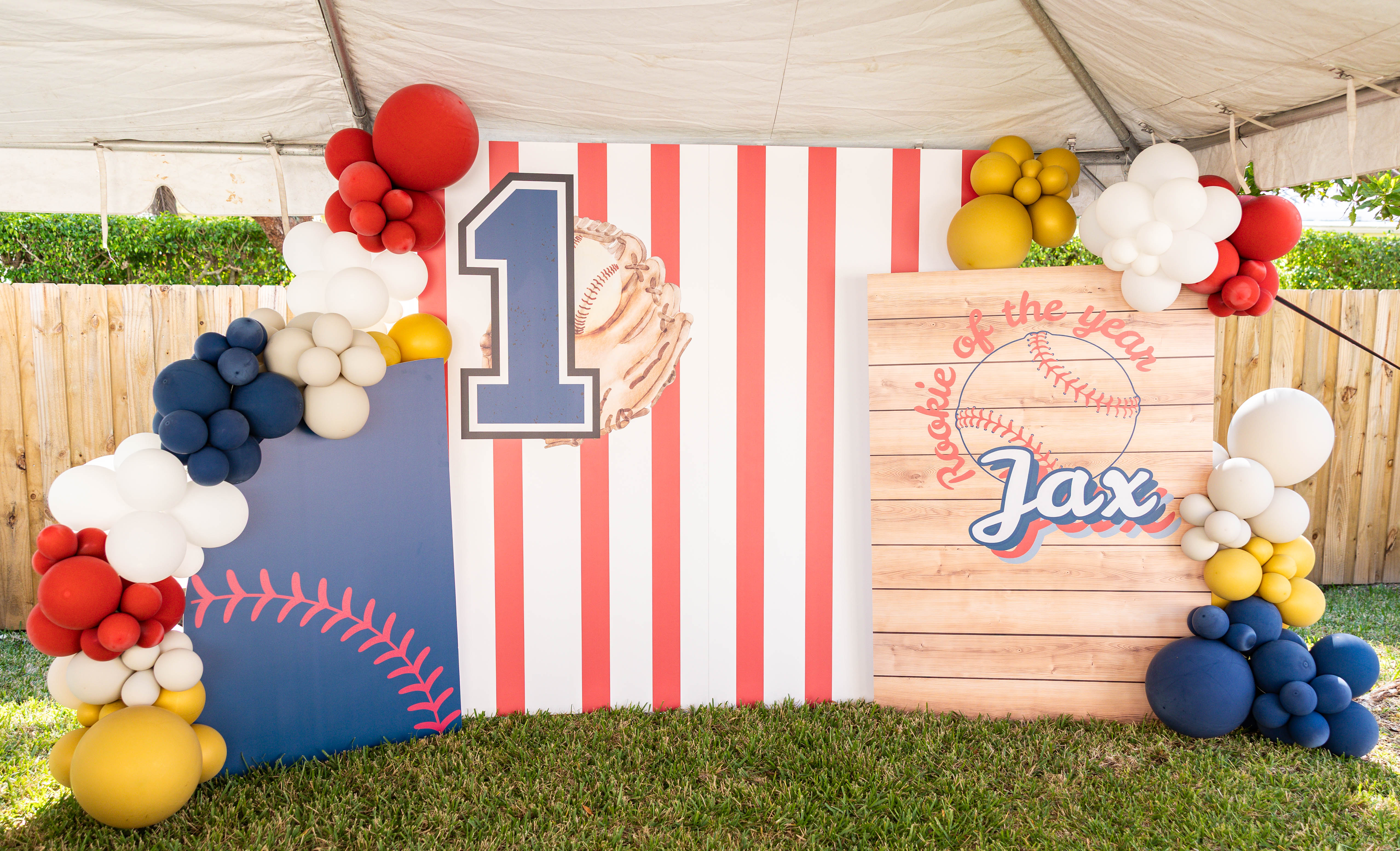 Baseball-themed first birthday party with custom backdrop and balloon clusters