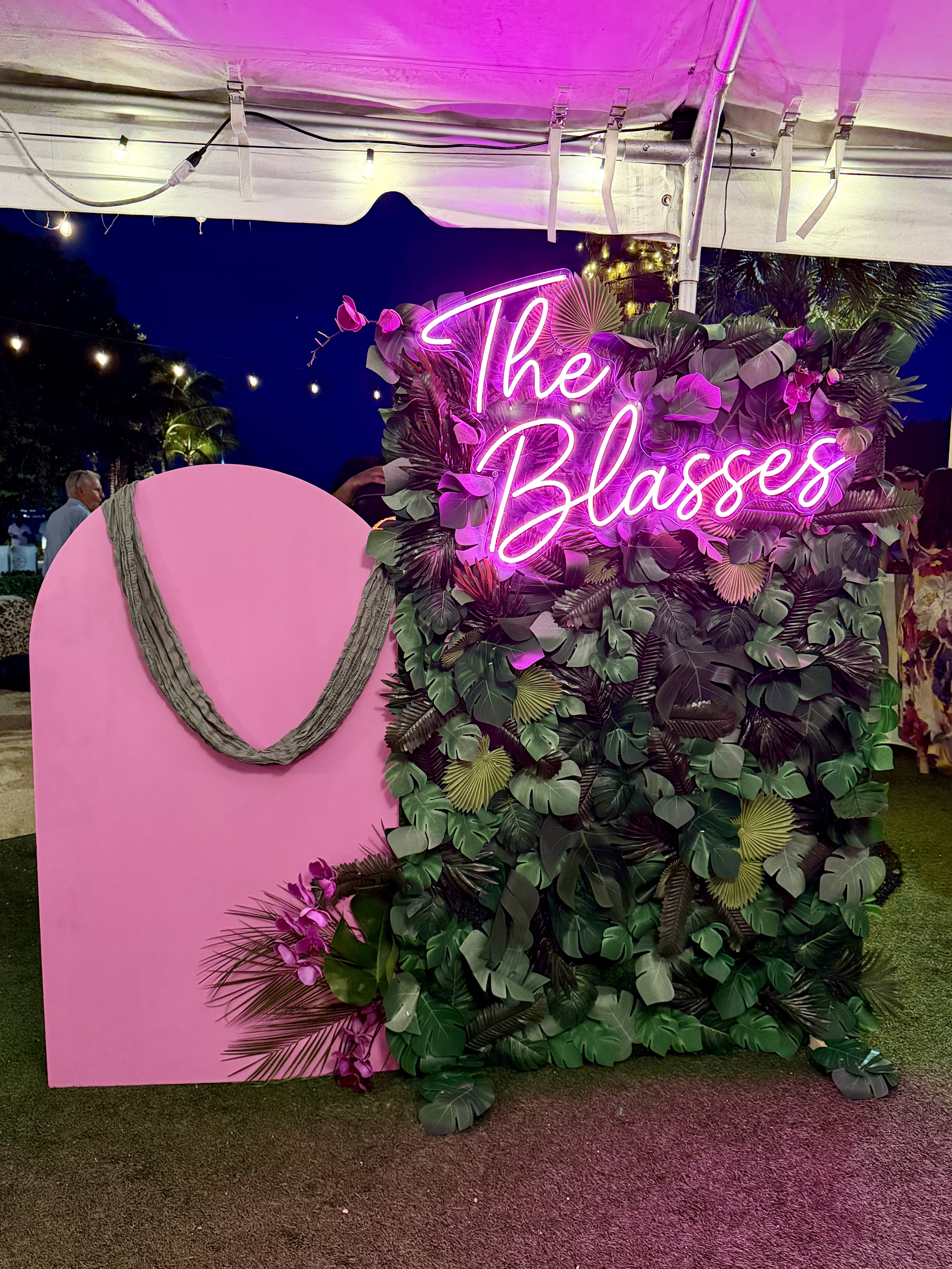 Custom neon sign backdrop with tropical greenery for a corporate event